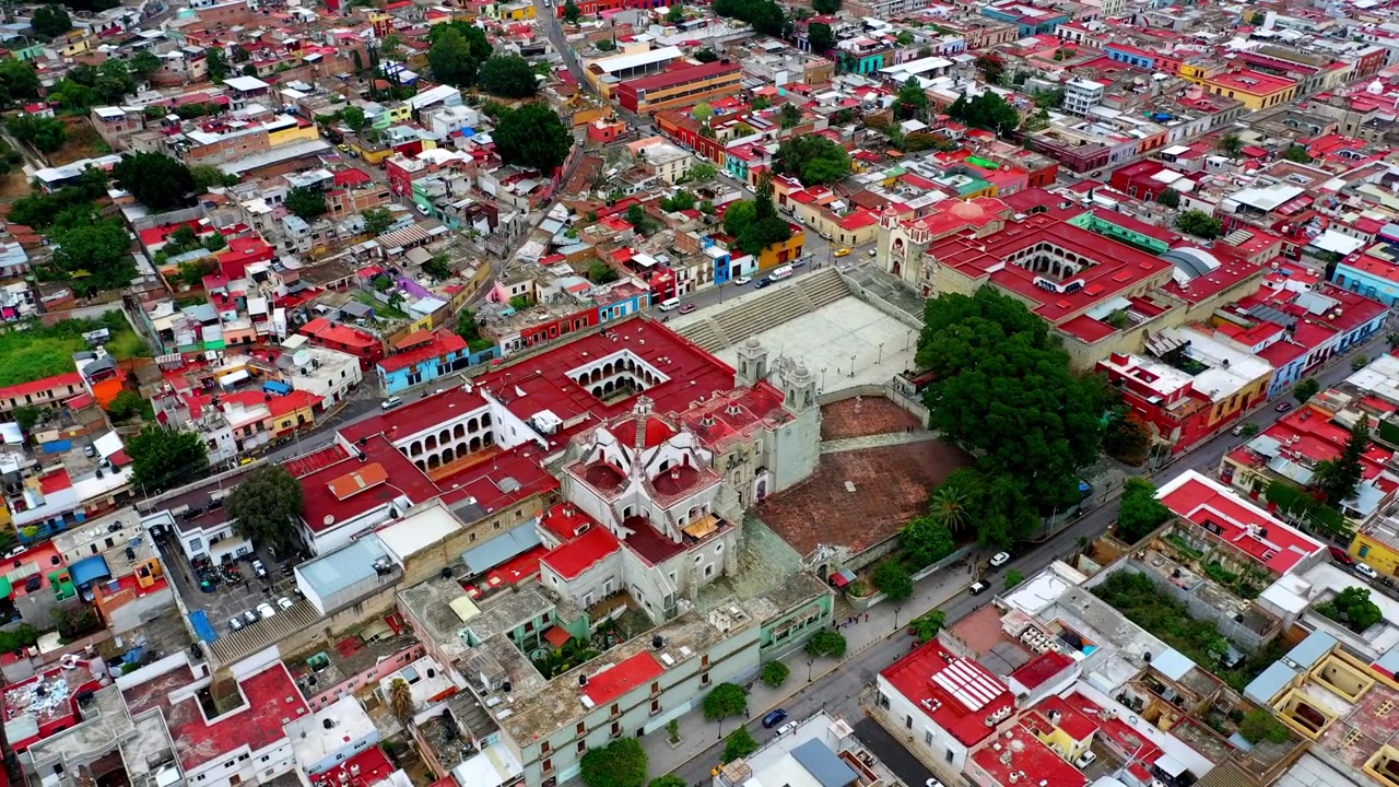 Ripresa aerea con drone del centro storico di Oaxaca con cattedrale, edifici colorati, strade urbane e architettura coloniale durante il giorno.