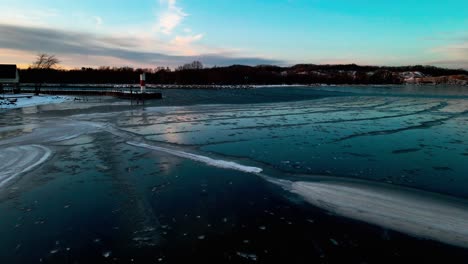 drone rising in stunning aerial over blue ice on a small lake