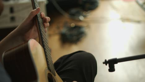 primer plano de un guitarrista profesional tocando un solo en una guitarra acústica occidental durante una sesión de grabación