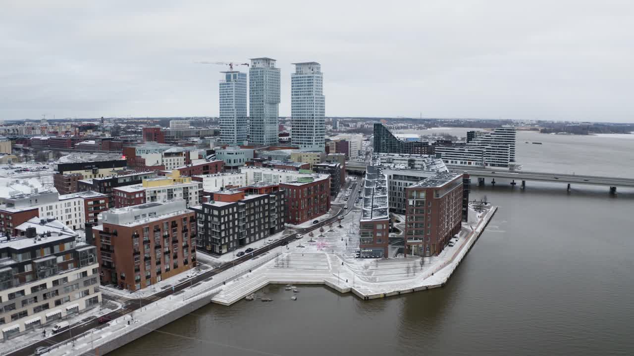 Aerial view following the snowy coast of the Kalasatama, winter day in Helsinki