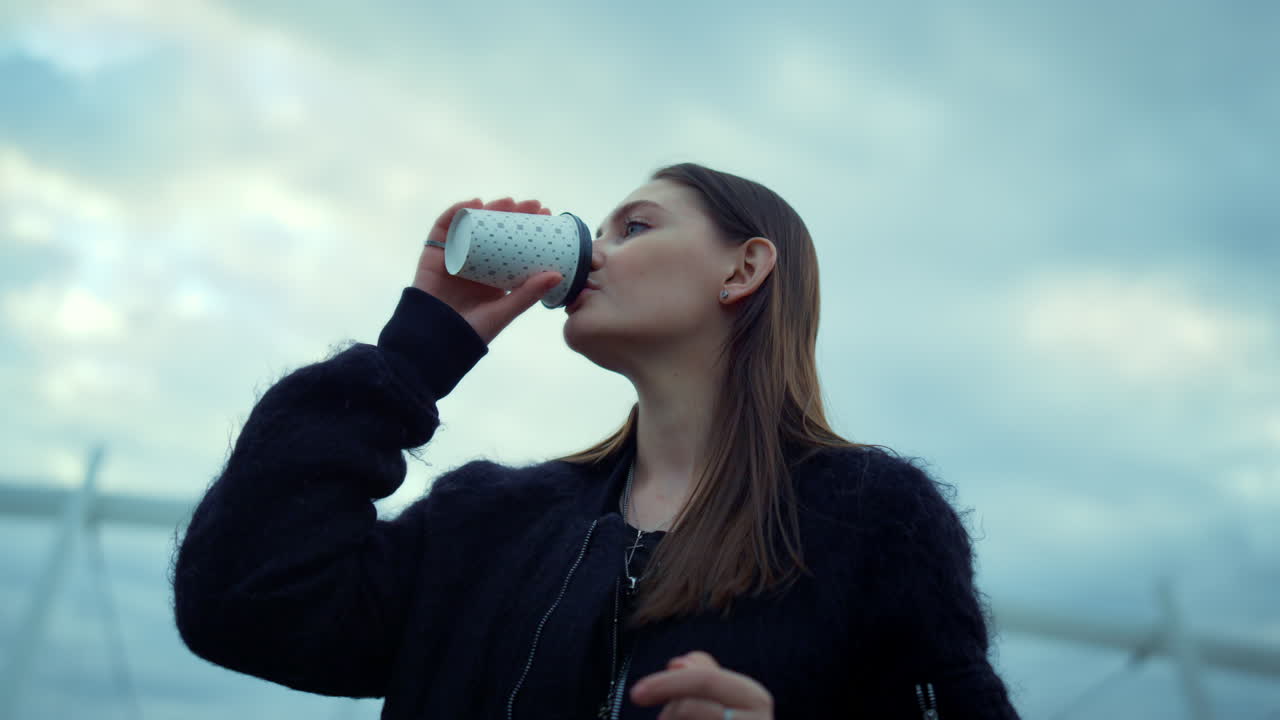 Girl drinking take away coffee on street. Woman checking time on wristwatch