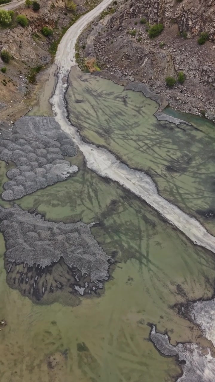Vista di un letto di fiume asciutto con rocce e acqua verde in una valle