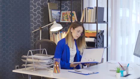 Office-worker-woman-looking-at-files-and-looking-at-computer.