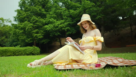 sexy woman sitting on blanket, smiling, reading book in park