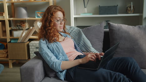 teenage girl using laptop on a couch