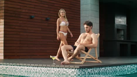 Handsome-man-using-mobile-phone-near-pool-at-luxury-house.