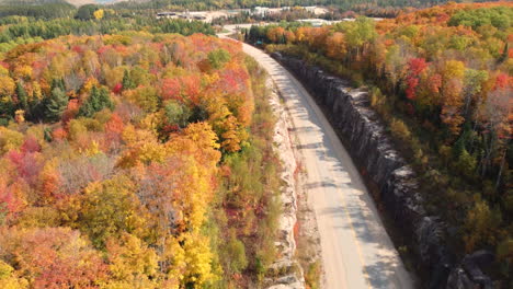 Vista-Aérea-Alrededor-De-Una-Carretera-En-Medio-Del-Follaje-Otoñal-En-El-Soleado-Canadá---Dando-Vueltas,-Disparo-De-Drones