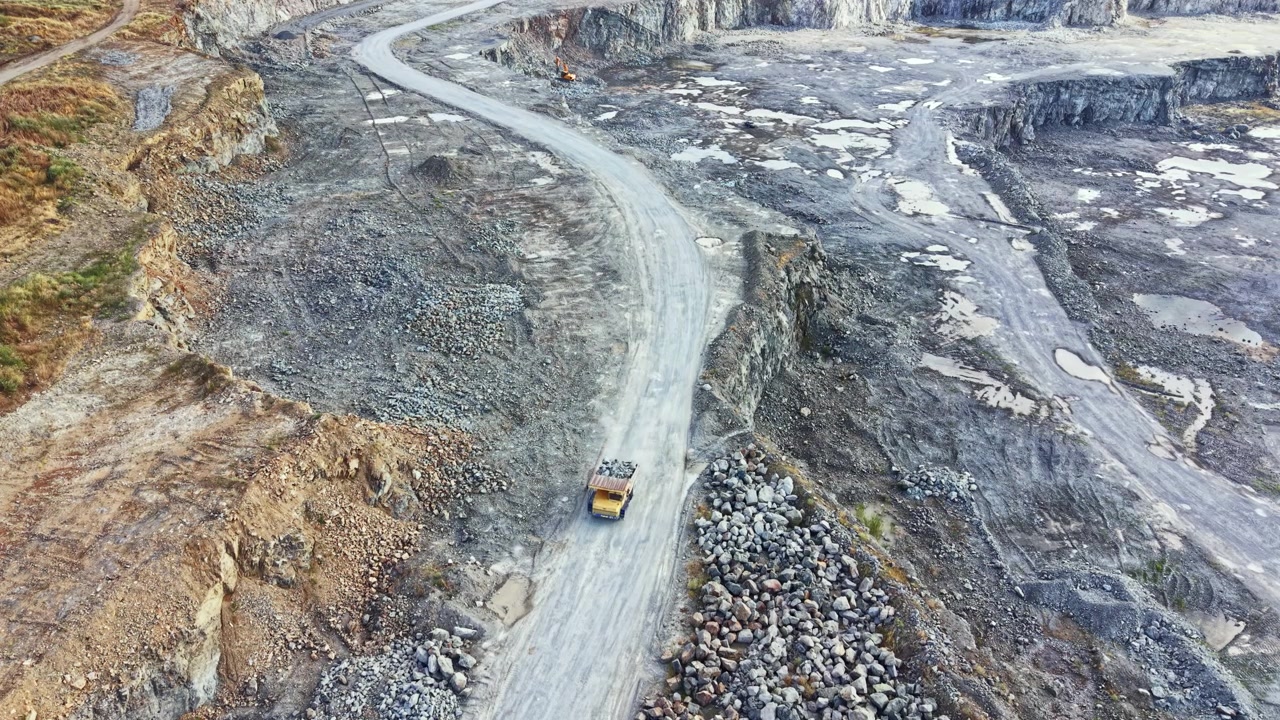 Granite quarry work site with truck driving on dirt road during daylight