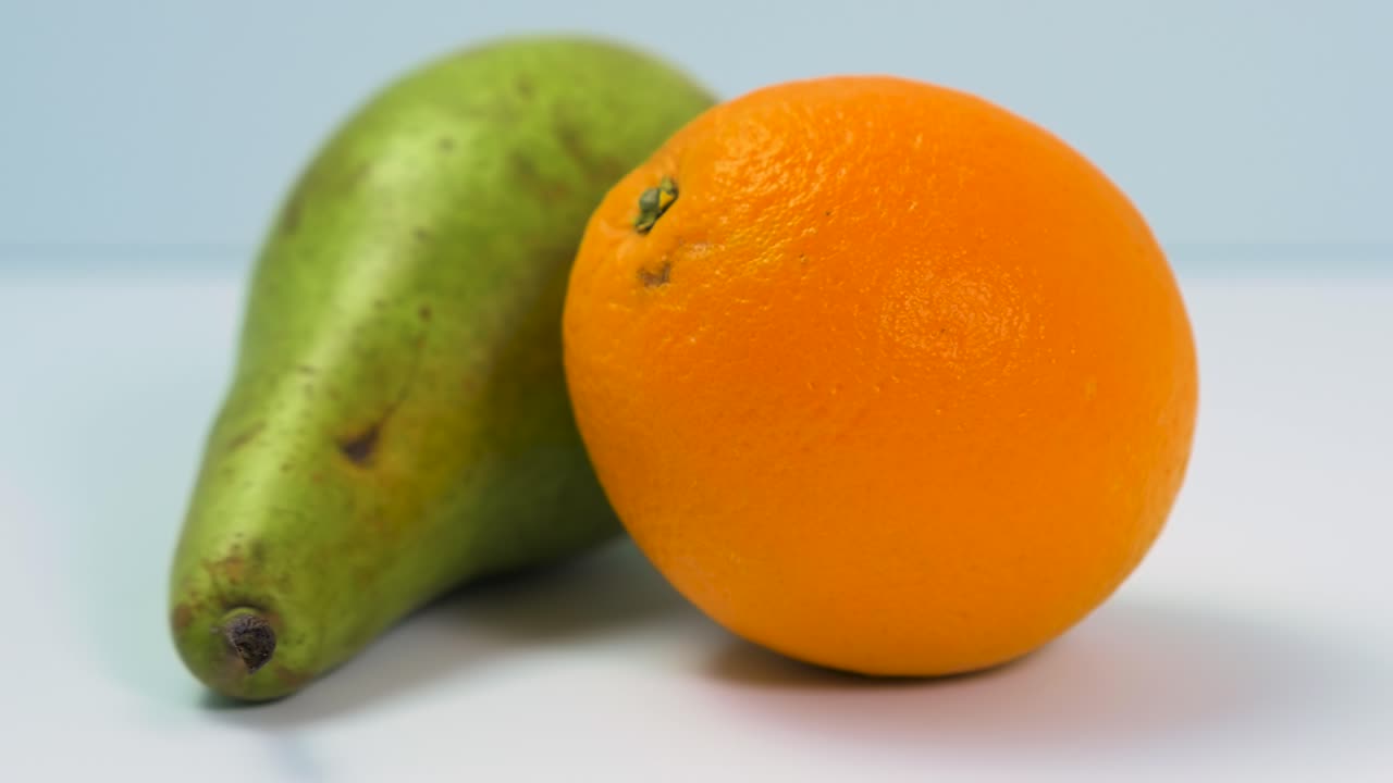 신선한 큰 녹색 배, 즙이 많은 오렌지는 밝은 파란색 배경, 건강한 음식 개념, 극단적인 클로즈업 샷, 카메라 오른쪽 회전