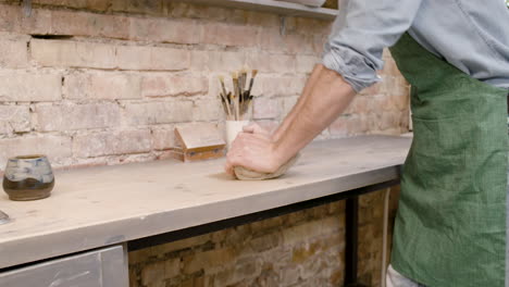 Close-Up-View-Of-The-Hands-Of-An-Clerk-Kneading-Clay-On-Top-Of-A-Table-In-A-Pottery-Workshop