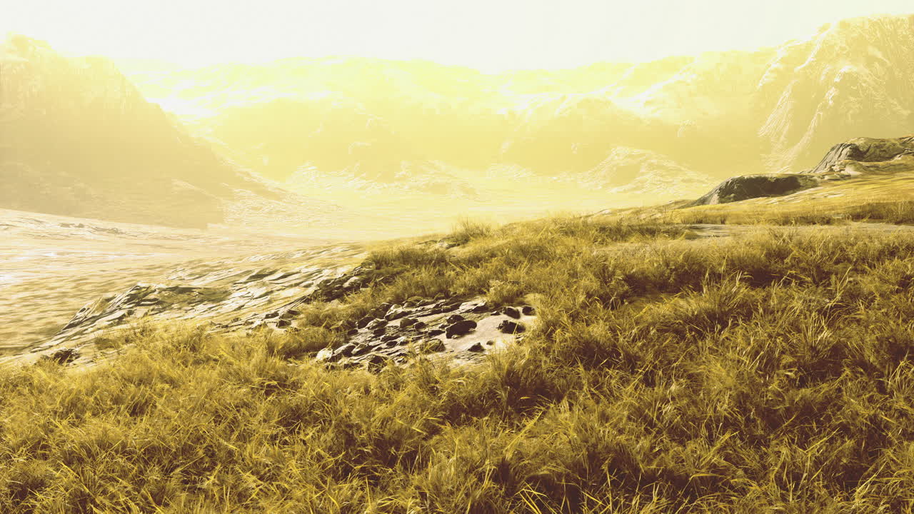 Golden sunlight illuminates grassy hills near majestic mountains