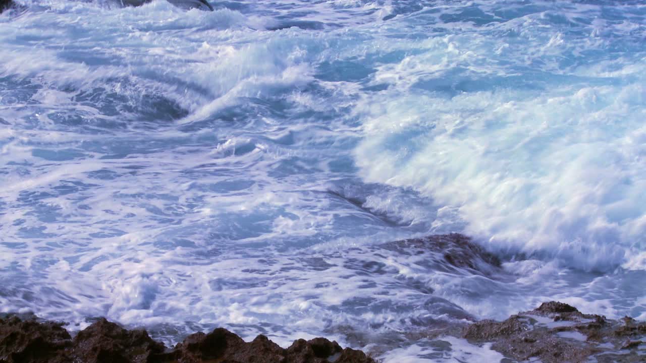 카메라가 세찬 파도에서 위로 기울어져 바다 옆에 서 있는 어부를 보여줍니다.