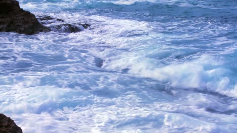 The-camera-tilts-up-from-pounding-ocean-waves-to-reveal-a-fisherman-standing-by-the-sea