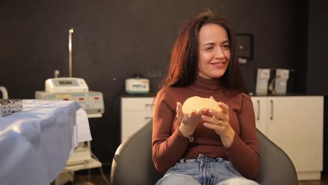 woman holding a breast implant in a medical office