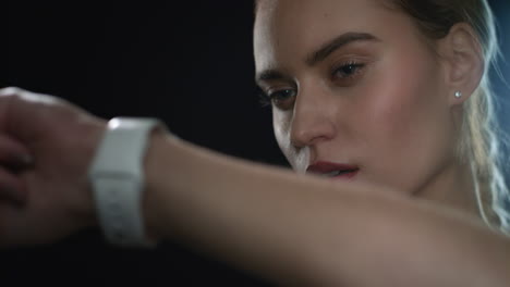 sport woman using smart watch on hand in black studio. portrait of fitness woman