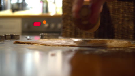 flattening gingerbread dough with rolling pin while preparing christmas cookies