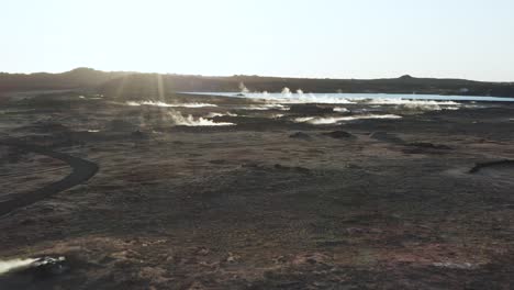 Scenic-volcanic-geyser-field-with-steam-rising-from-holes-during-bright-sunset