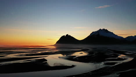 Rising-over-the-beautiful-sunset-rivers-nest-by-Brunnhorn-Mountain-in-South-East-Iceland---aerial-ascend