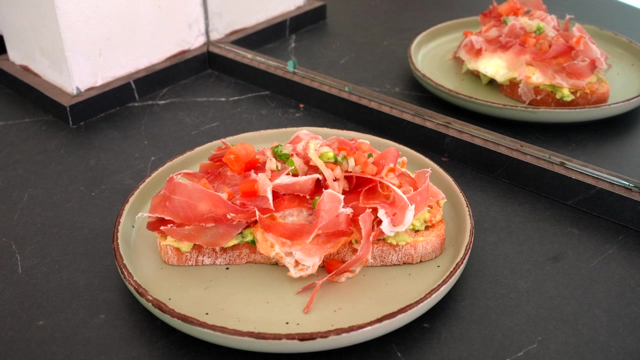 Avocado toast gourmet con prosciutto e condimenti freschi