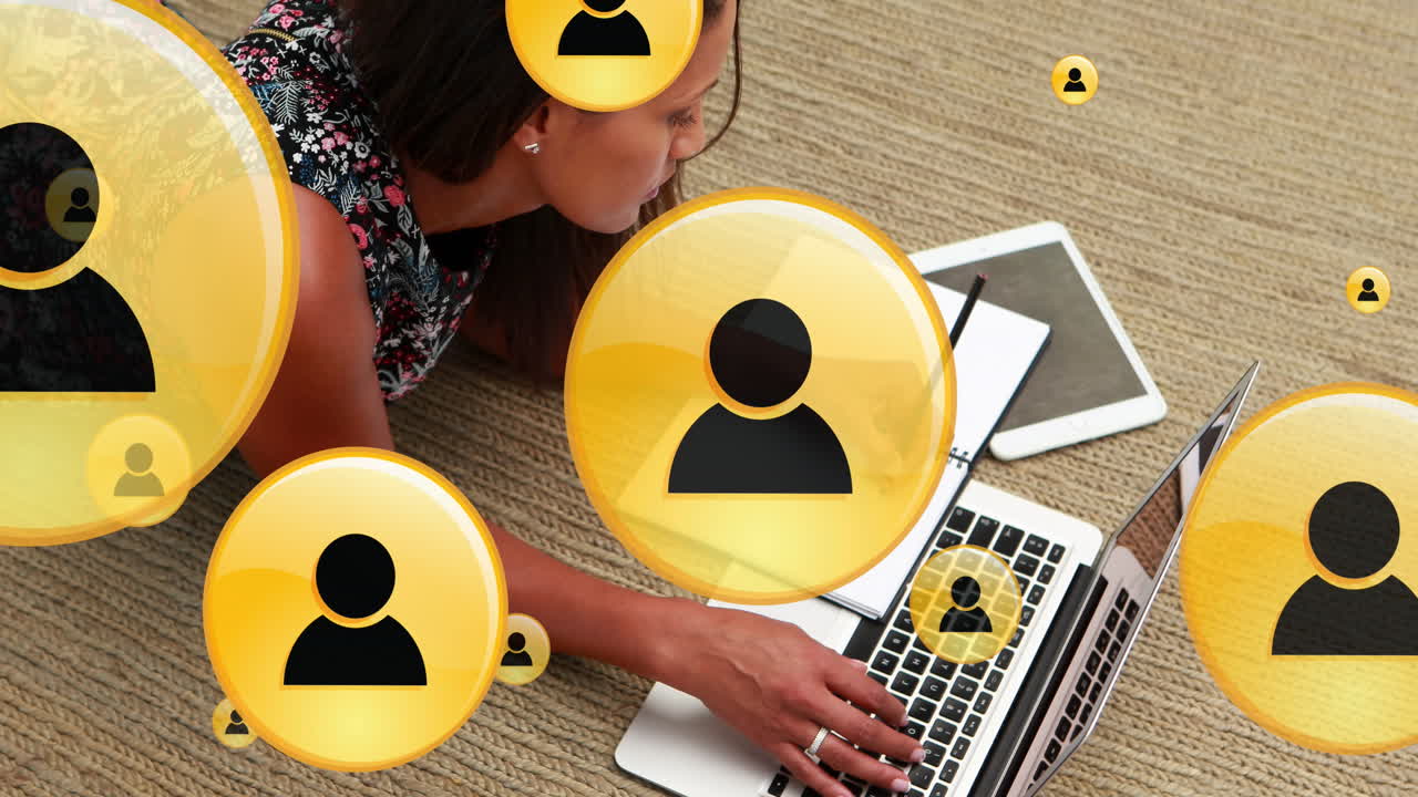 Animation of profile icons over biracial woman lying on floor with laptop and writing on notepad