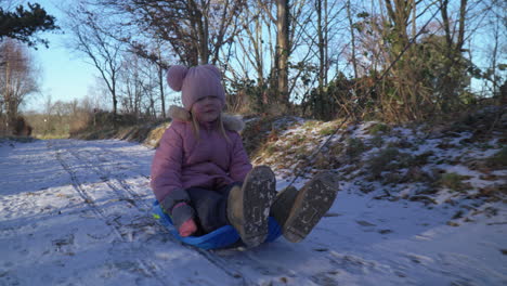 Girl-in-bobsled-being-pulled-on-snow-covered-path