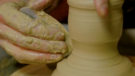 professional potter shaping mug with special tool in pottery workshop