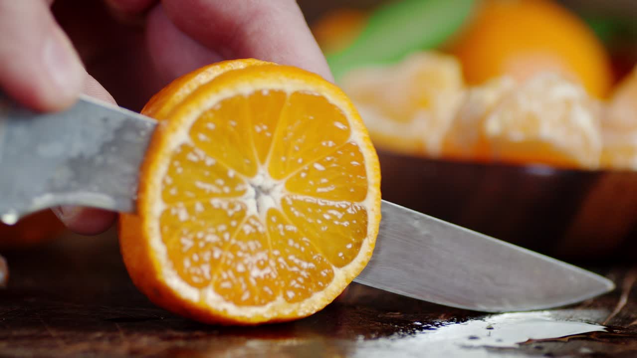 Men's hands cut Mandarin on a cutting Board into pieces.