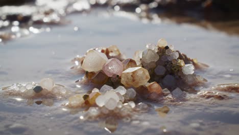 glittering gems on a serene shoreline: a close-up of vibrant pearls and crystals surrounded by gentle ocean waves and soft reflections