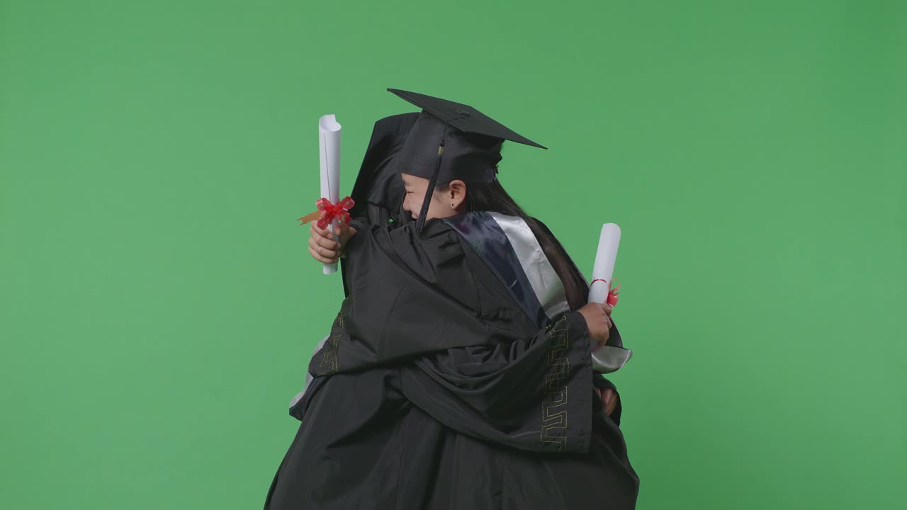 Asian Woman Students Graduate In Caps And Gowns With Diplomas Smiling And Hugging Each Other On The Green Screen Background In The Studio