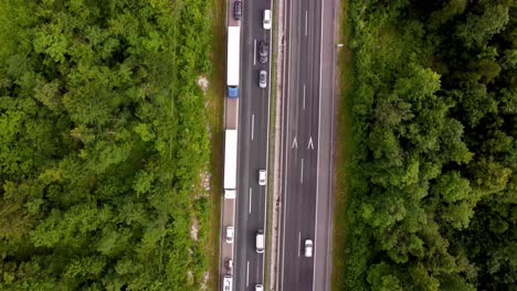 Top-down-drone-shot-of-small-highway-in-Europe-with-a-lot-of-trees-surrounding-the-national-road