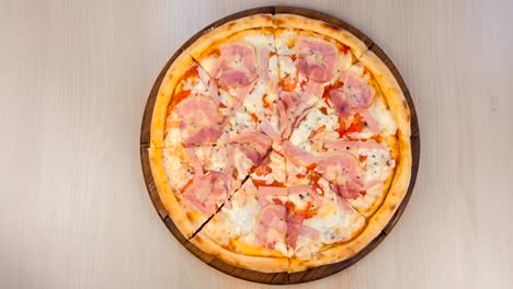 pizza con tocino y queso en una tabla de madera en la mesa.