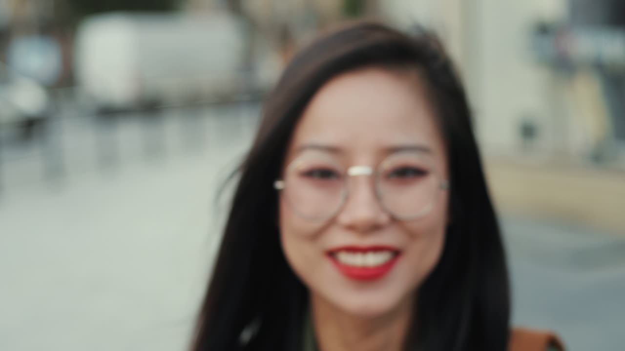 야외에서 카메라를 향해 행복하게 웃고 있는 빨간 입술을 가진 매력적인 젊은 여성의 초상화