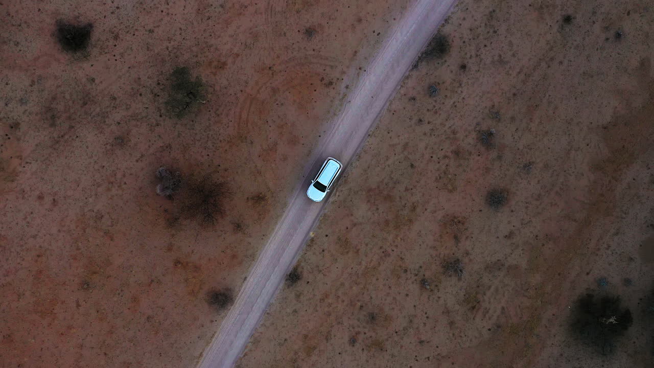 Vista aerea sopra un'auto su una strada di prateria remota, in Africa - ripresa zenitale, con drone.