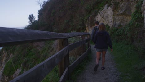 una pareja camina por un sendero en un acantilado marino 1