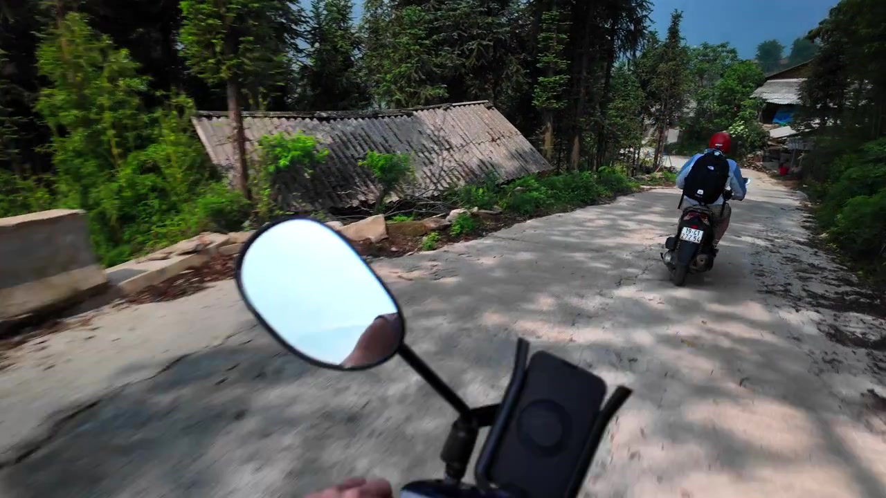Motocicletta che viaggia lungo una strada di montagna rustica attraverso un villaggio a Sa Pa, Vietnam. Ripresa POV.