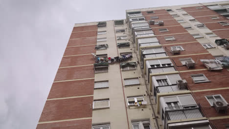 beautiful slow motion zoom in shot from below to the top of a building in the barrio del pilar in madrid, an urban area with hanging clothes.