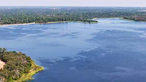 flying back and to the right, across a section of trees that encompass a bright blue section of lake