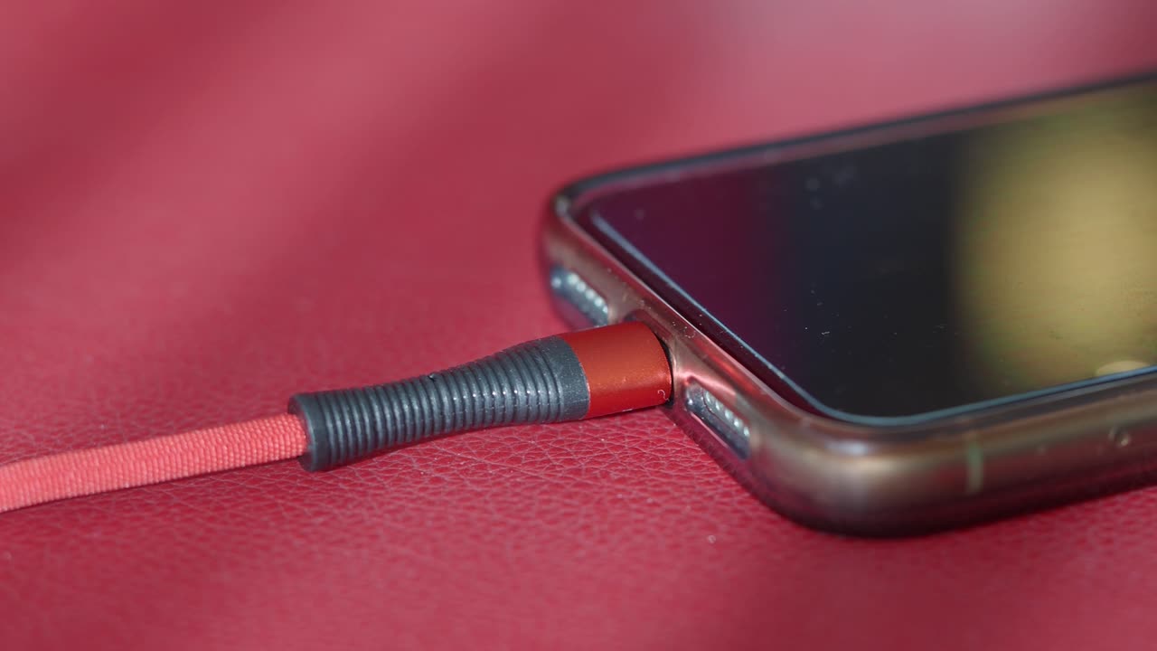Primo piano di uno smartphone in carica su una superficie rossa