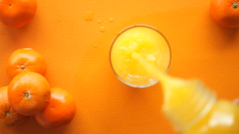 vertiendo jugo de naranja en un vaso con naranjas