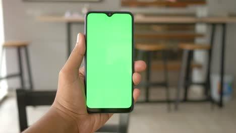 close up de la mano de un joven usando un teléfono inteligente con pantalla verde