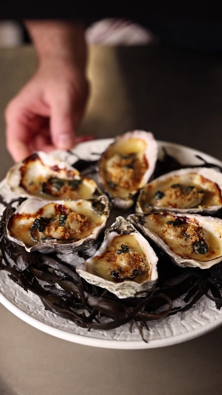 Chef Presenting Baked Oysters on a Bed of Seaweed
