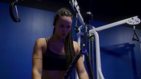 close up of a girl in the gym using a cable machine while breathing heavily