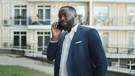 serious african businessman talking on phone outside. man having conversation