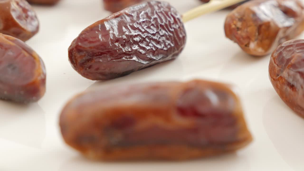 Palm dates exotic fruit on white background slow tilt 4K