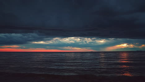 Hermosa-Cinemagrafía-De-4k-Uhd:-Bucle-De-Video-Continuo-De-La-Puesta-De-Sol-Vista-Desde-Una-Playa-Romántica-Con-Pequeñas-Olas-En-La-Costa-Mediterránea-Croata-Con-Nubes-Oscuras-De-Tormenta-Mezcladas-Con-Rojo