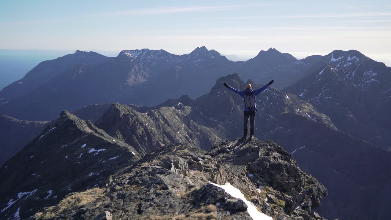 un excursionista alcanzó la cima y extendió sus brazos en la cresta de la montaña cuillin en escocia