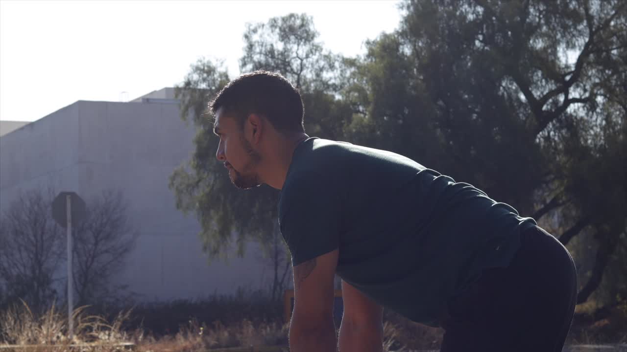 Mexican sports man lifting dumbbells out doors