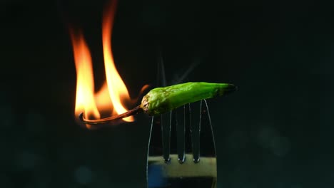 close-up-slow-motion-spicy-hot-green-pepper-on-fire-at-the-tip-of-fork