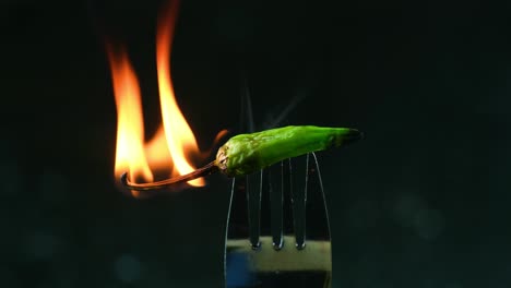 primer plano en cámara lenta pimienta verde picante picante en llamas en la punta del tenedor