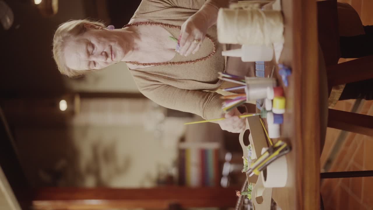 Elderly woman crafting flowers at a table